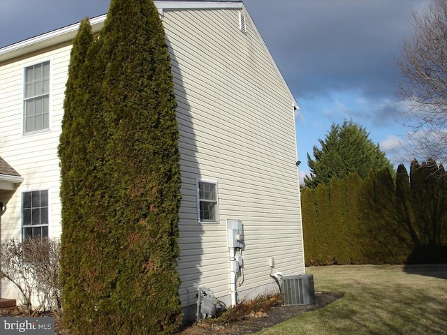 view of side of property featuring central AC unit and a lawn