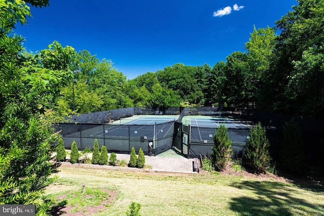 view of sport court with a lawn and fence