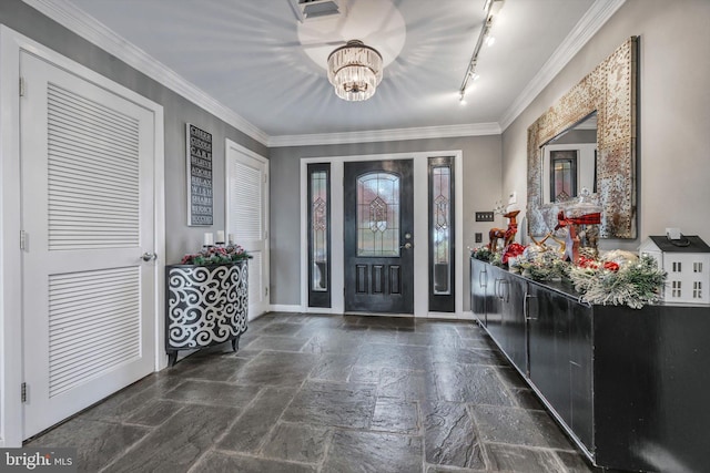 entryway with ornamental molding, track lighting, and an inviting chandelier