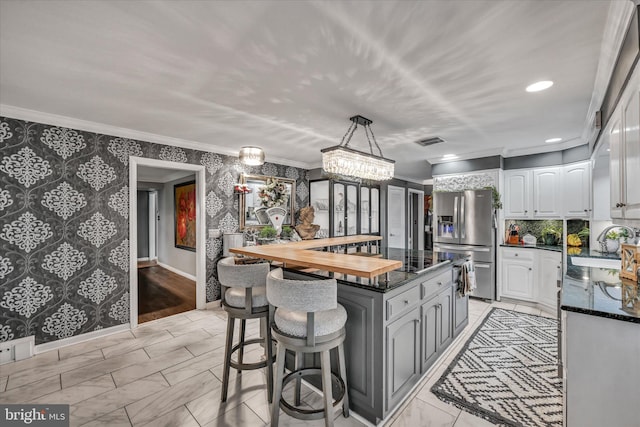 kitchen with a center island, sink, stainless steel fridge, butcher block countertops, and white cabinetry