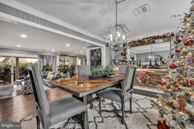 dining space with hardwood / wood-style floors, an inviting chandelier, and ornamental molding