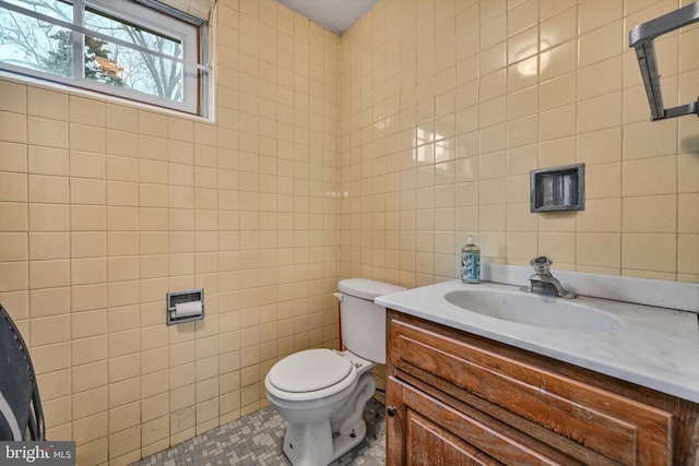 bathroom with vanity, toilet, and tile walls