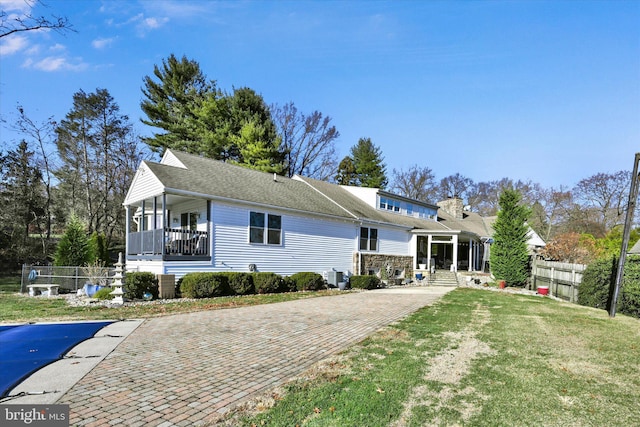 view of front of property featuring a sunroom, a front lawn, and central AC unit