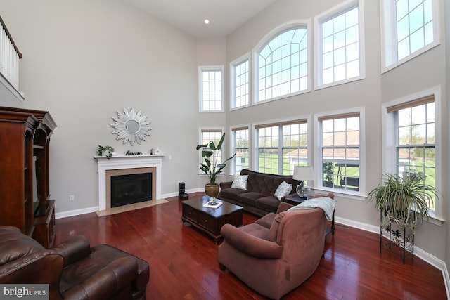 living room with a towering ceiling, dark hardwood / wood-style floors, and a healthy amount of sunlight