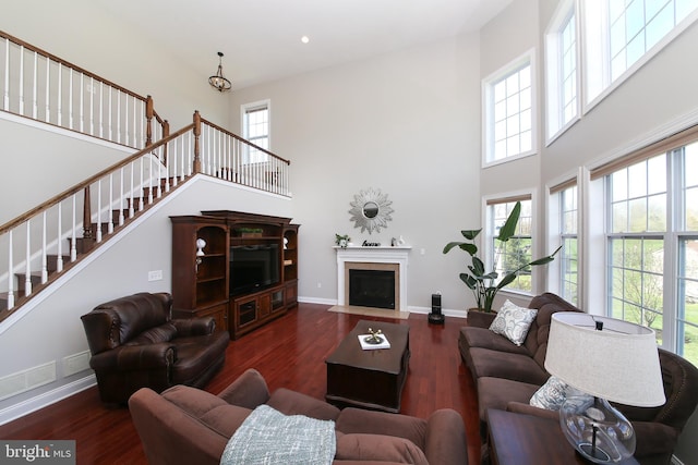 living room featuring a high ceiling, dark hardwood / wood-style flooring, and an inviting chandelier