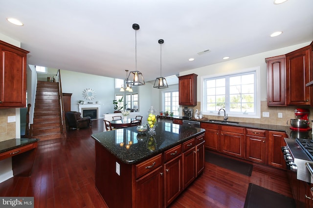 kitchen with a center island, sink, hanging light fixtures, tasteful backsplash, and dark hardwood / wood-style flooring