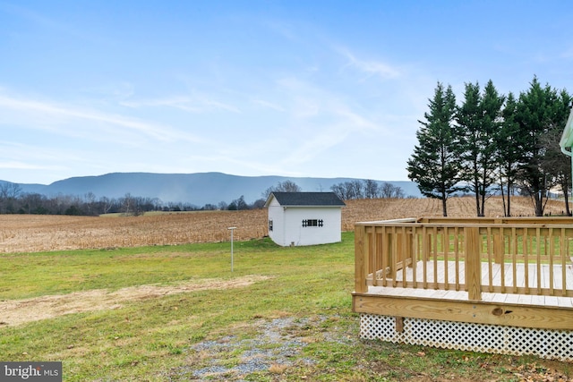 view of yard with a deck with mountain view, a rural view, and a storage shed