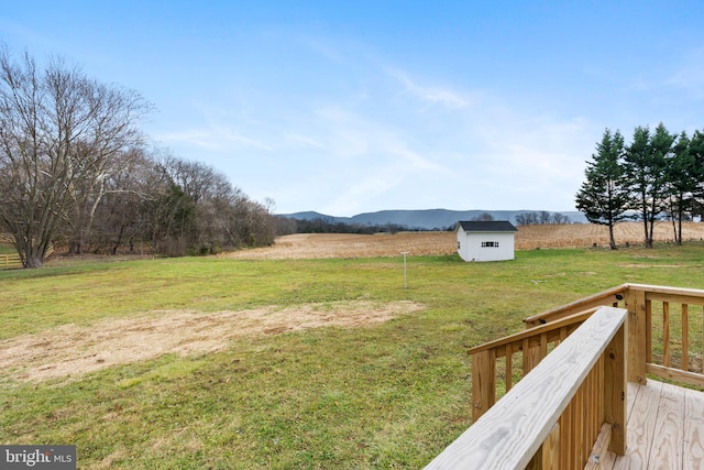 view of yard with a deck with mountain view, a rural view, and a shed