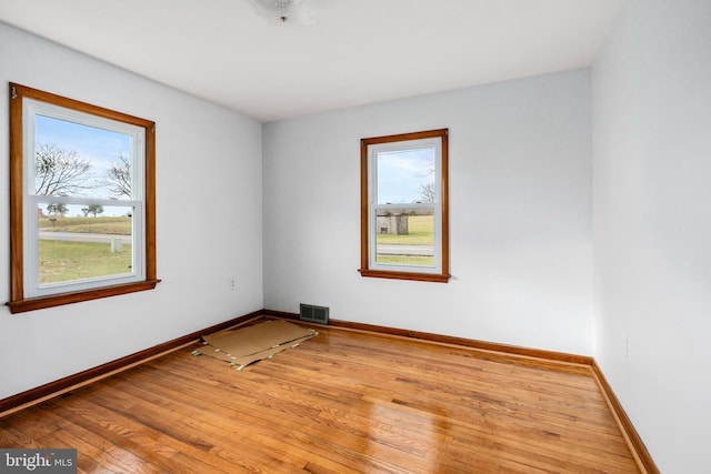 spare room with plenty of natural light and light hardwood / wood-style flooring