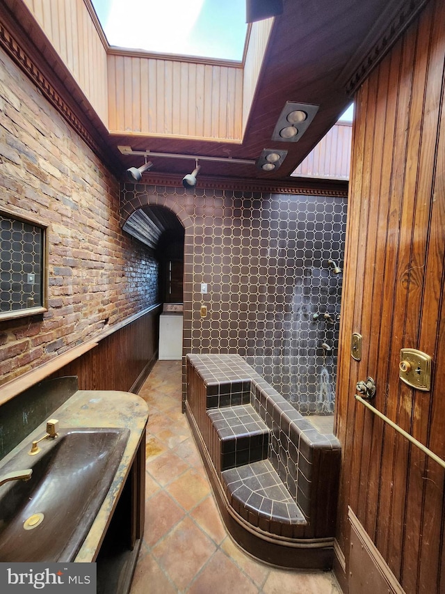 bathroom with walk in shower, vanity, and wooden walls