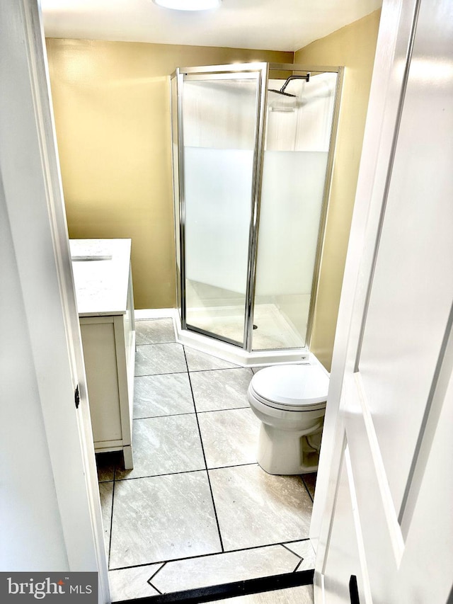 bathroom featuring tile patterned floors, vanity, toilet, and walk in shower