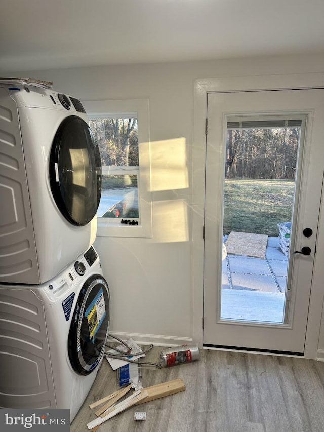 clothes washing area featuring stacked washer / dryer and light hardwood / wood-style flooring