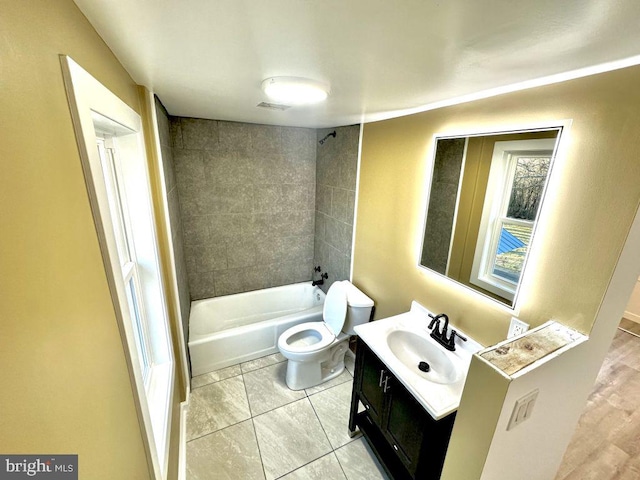 full bathroom featuring tile patterned flooring, vanity, tiled shower / bath combo, and toilet