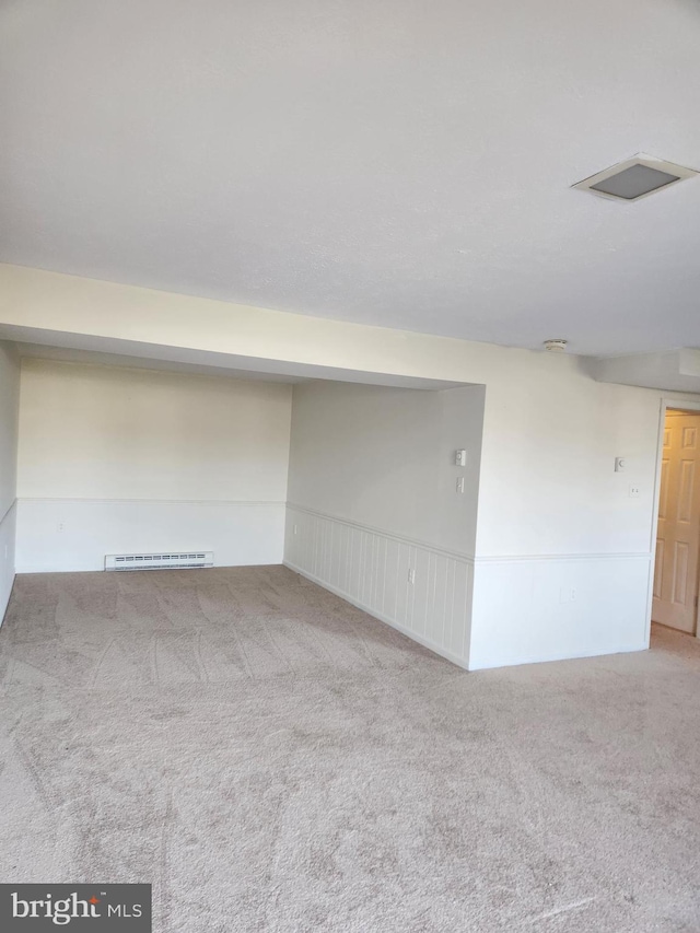 carpeted spare room with a baseboard heating unit