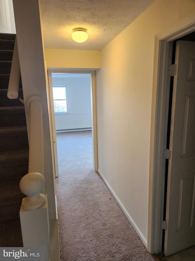 corridor featuring carpet flooring, a textured ceiling, and a baseboard heating unit