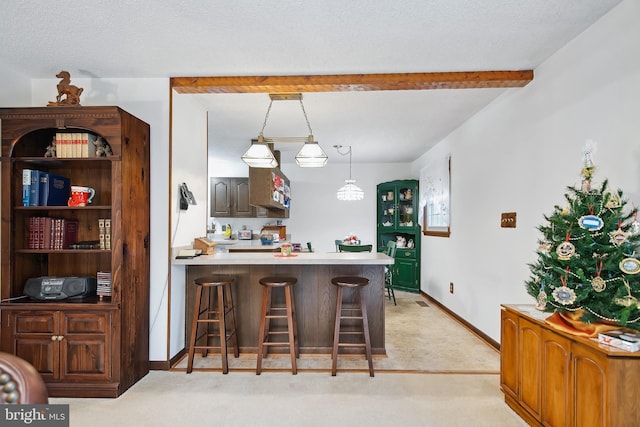 kitchen with hanging light fixtures, beamed ceiling, kitchen peninsula, a breakfast bar area, and light carpet