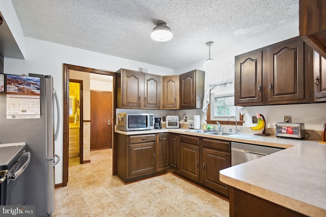 kitchen featuring stainless steel appliances, sink, hanging light fixtures, and dark brown cabinets