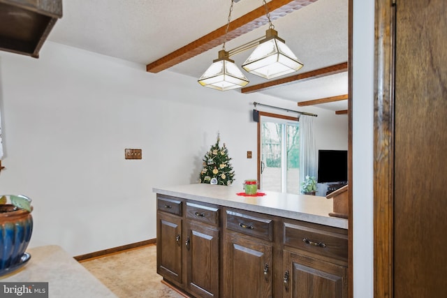 kitchen with pendant lighting, dark brown cabinetry, and beamed ceiling