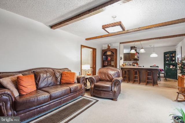 living room featuring beam ceiling, light colored carpet, a textured ceiling, and bar area