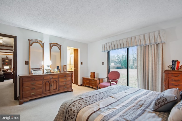 bedroom with a textured ceiling, access to outside, and light colored carpet