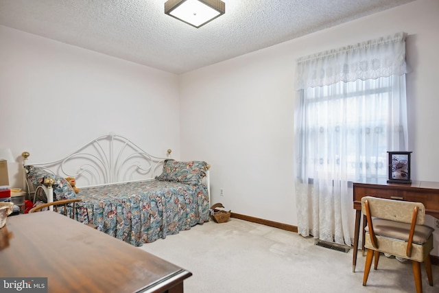 bedroom featuring a textured ceiling and light carpet