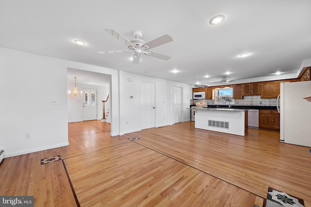 kitchen with white appliances, ceiling fan with notable chandelier, decorative backsplash, light wood-type flooring, and a kitchen island