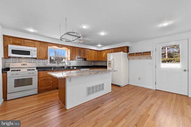 kitchen with plenty of natural light, white appliances, sink, and light hardwood / wood-style flooring