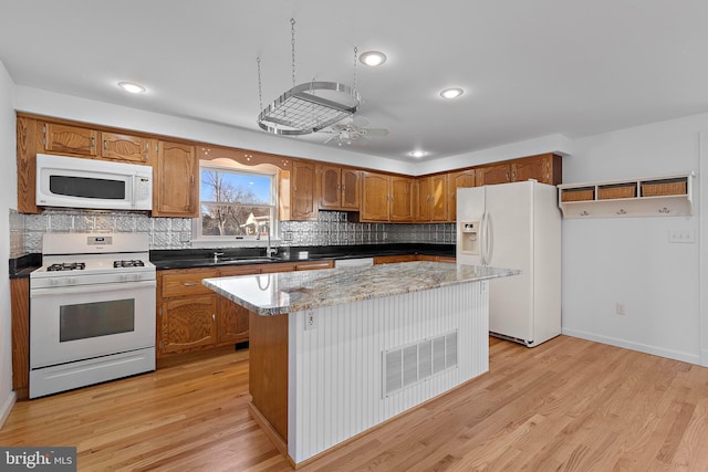 kitchen featuring light wood-type flooring, white appliances, ceiling fan, sink, and a center island