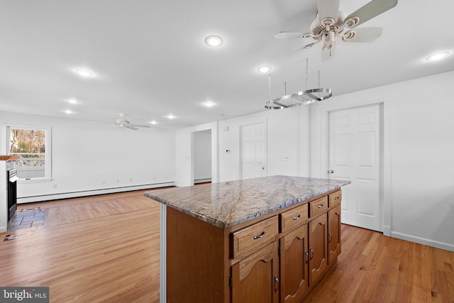 kitchen featuring baseboard heating, light stone counters, a center island, and light hardwood / wood-style flooring