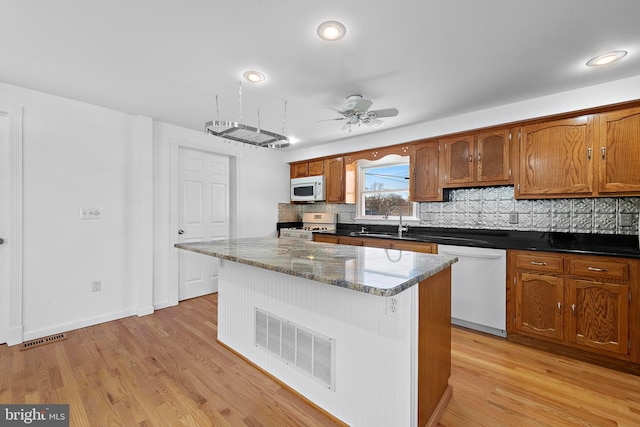 kitchen featuring ceiling fan, a center island, sink, light hardwood / wood-style floors, and white appliances