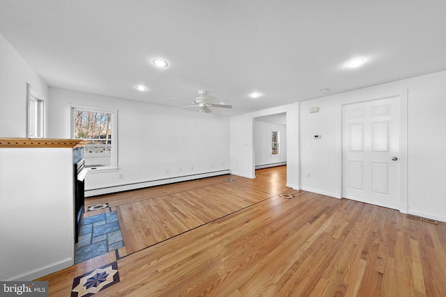 unfurnished living room with ceiling fan, light hardwood / wood-style flooring, and a baseboard heating unit