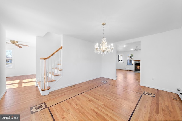 unfurnished dining area featuring ceiling fan with notable chandelier, hardwood / wood-style flooring, and a baseboard heating unit