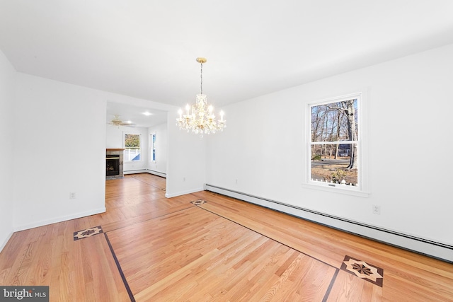 unfurnished dining area with hardwood / wood-style flooring, ceiling fan with notable chandelier, and a baseboard radiator