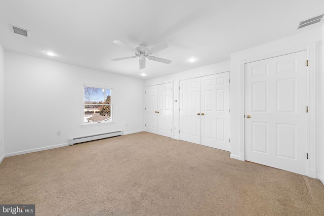 unfurnished bedroom featuring carpet, ceiling fan, multiple closets, and a baseboard heating unit