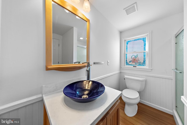 bathroom featuring hardwood / wood-style floors, vanity, toilet, and walk in shower