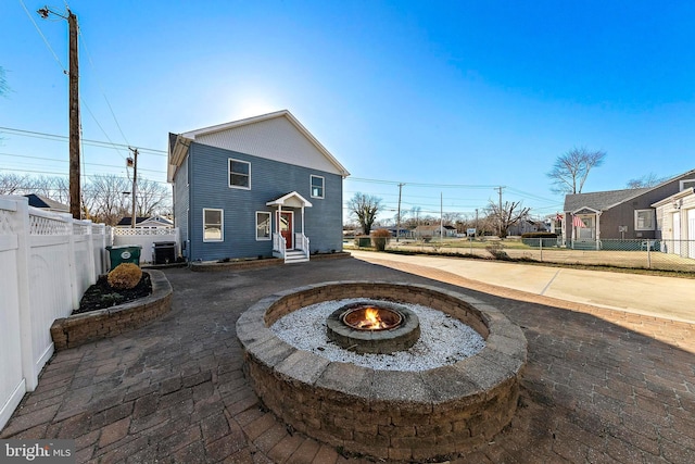 back of property featuring central AC unit and an outdoor fire pit