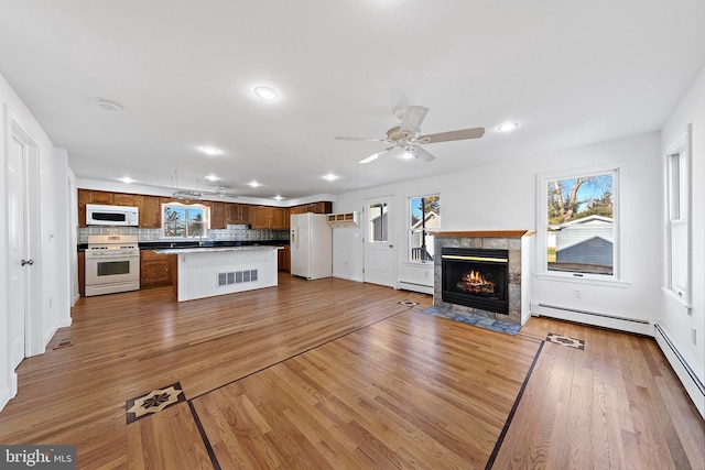 unfurnished living room featuring light hardwood / wood-style flooring, plenty of natural light, and a baseboard heating unit