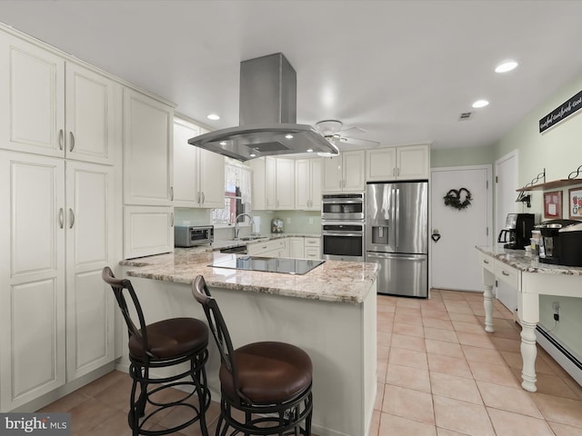 kitchen featuring light stone countertops, white cabinets, appliances with stainless steel finishes, sink, and island range hood