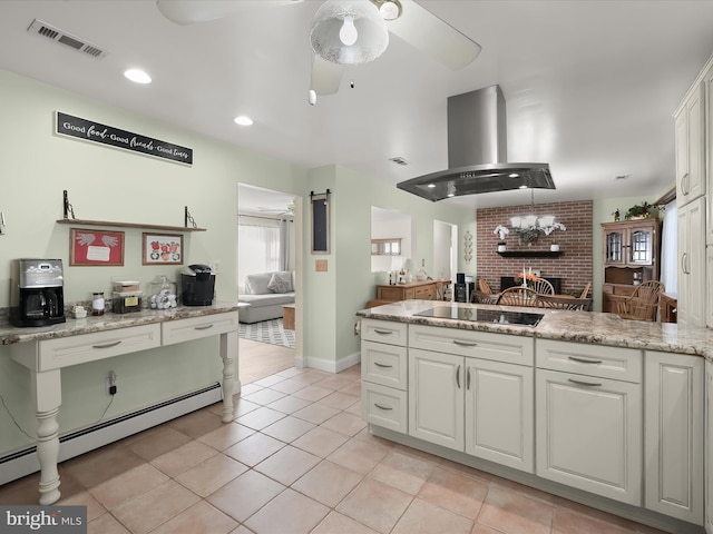 kitchen featuring extractor fan, a barn door, light tile patterned floors, black electric cooktop, and white cabinets