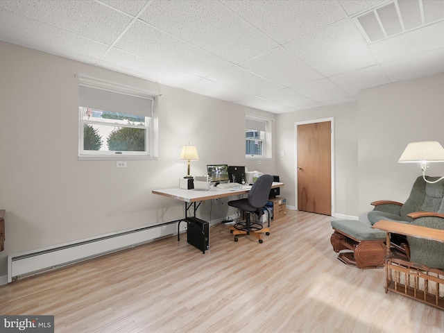 office with light hardwood / wood-style flooring, a baseboard radiator, and a drop ceiling