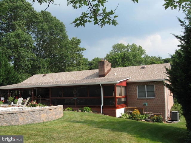 rear view of house with cooling unit, a sunroom, and a yard