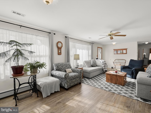 living room with hardwood / wood-style flooring, a baseboard radiator, and ceiling fan