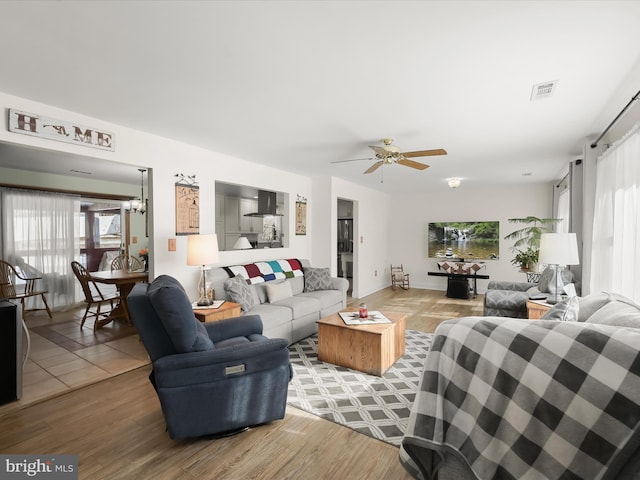 living room with hardwood / wood-style flooring and ceiling fan with notable chandelier