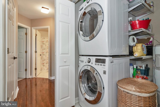 laundry area with stacked washer / dryer and wood-type flooring