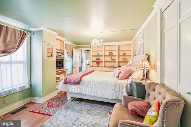 bedroom featuring light wood-type flooring, an inviting chandelier, a closet, and crown molding