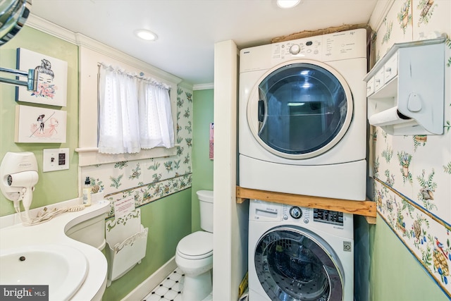 laundry room with tile patterned flooring, stacked washer and dryer, crown molding, and sink