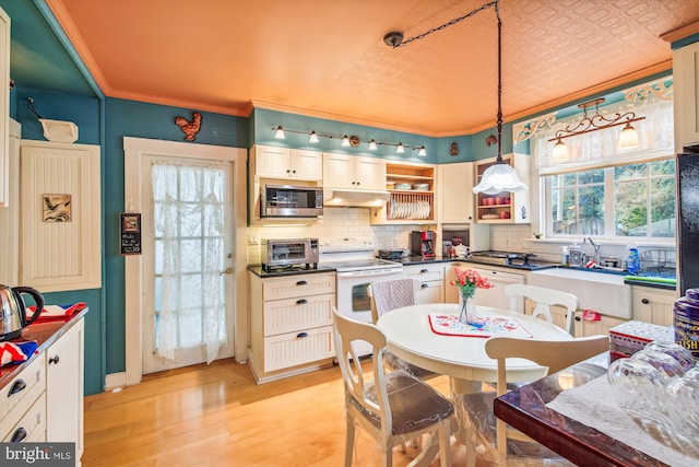 kitchen with pendant lighting, white appliances, light hardwood / wood-style flooring, decorative backsplash, and ornamental molding