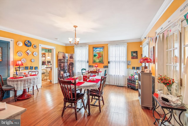 dining area featuring crown molding, light hardwood / wood-style floors, and an inviting chandelier