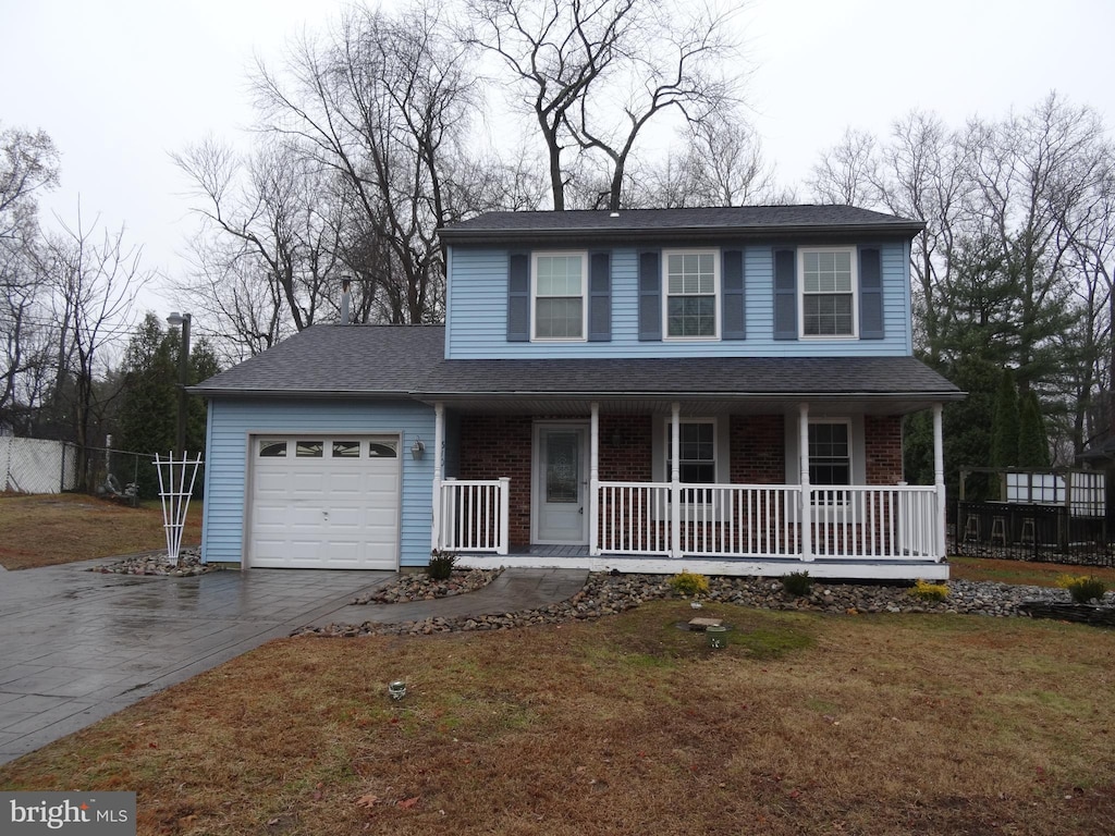 view of front facade with covered porch, a garage, and a front yard