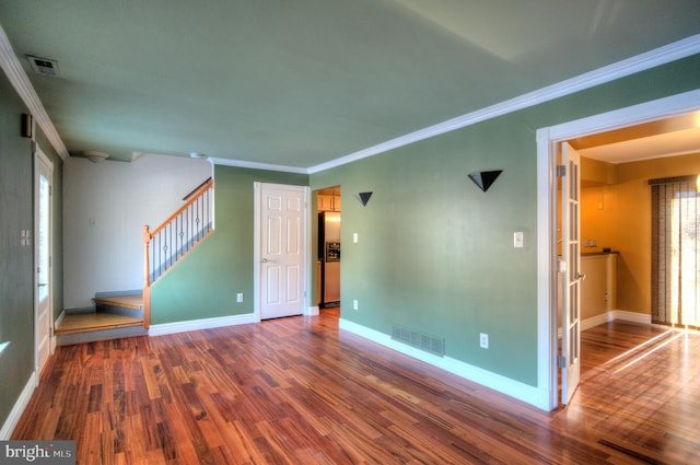 spare room featuring wood-type flooring, crown molding, and a healthy amount of sunlight